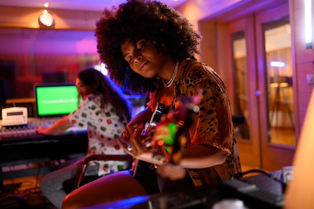 A multicultural bass player recording a part of her song in a music studio.