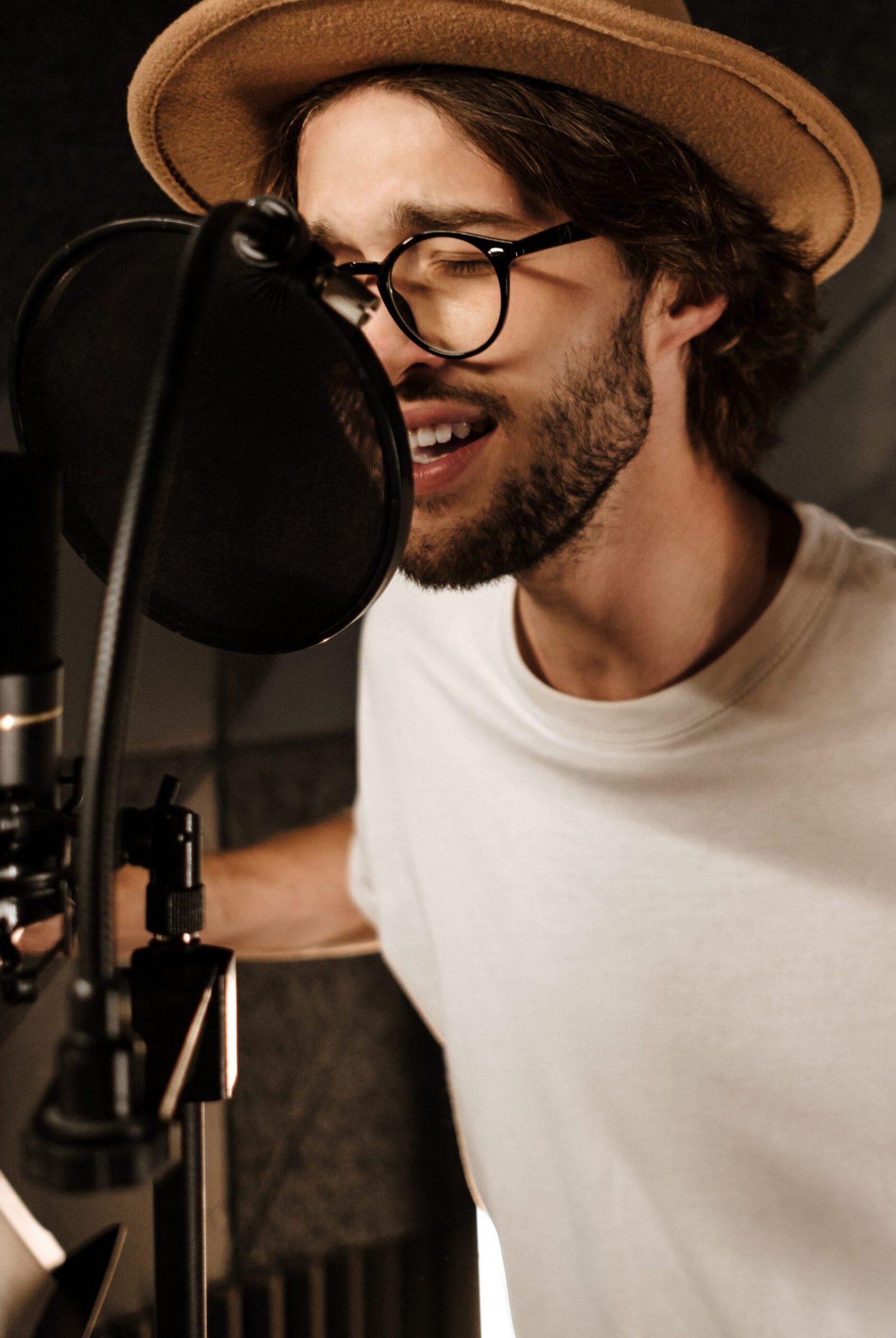 Handsome stylish male musician emotionally singing in microphone recording song in studio